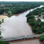 Rio Aquidauana em período de cheia, com aumento do nível da água e áreas urbanas próximas às margens.